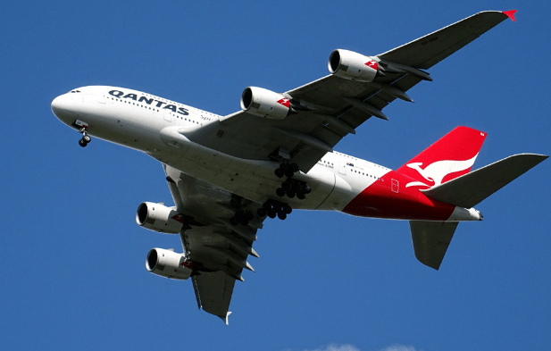 A large airplane soaring through a clear blue sky, showcasing its wings and fuselage against the backdrop of clouds