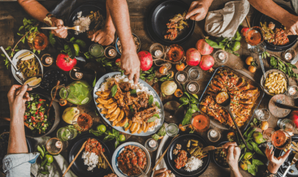 A diverse group of people enjoying a meal together around a table filled with various dishes and drinks