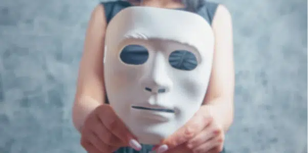 Person holding a white mask symbolizing pretending to be someone else.
