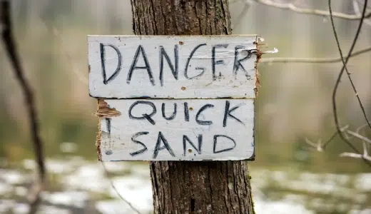 A person hesitating at a crossroads, symbolizing the hidden risks of always playing it safe instead of taking bold action.